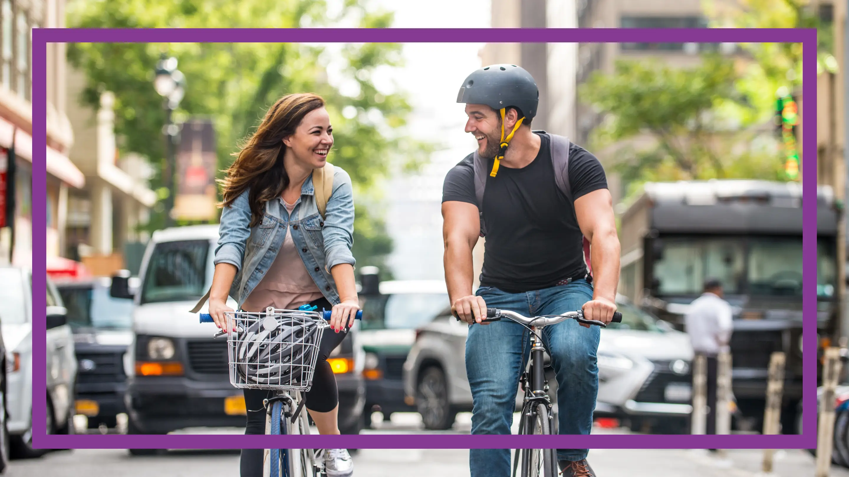 A young woman and a young man cycling on a city street.
